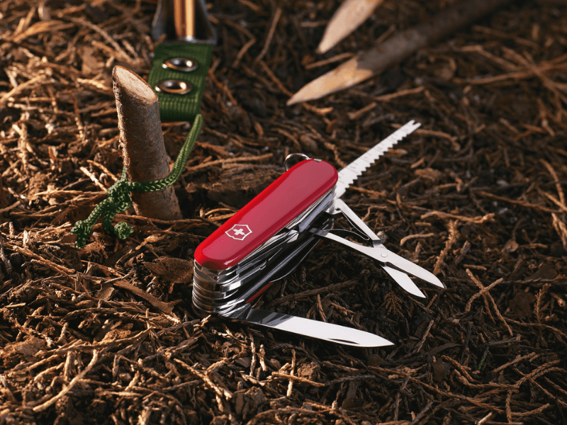 mittleres taschenmesser swiss champ rot auf waldboden vor zelt zum campen verwenden