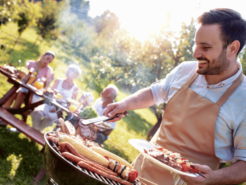 grillen-mann grillt mit familie im garten