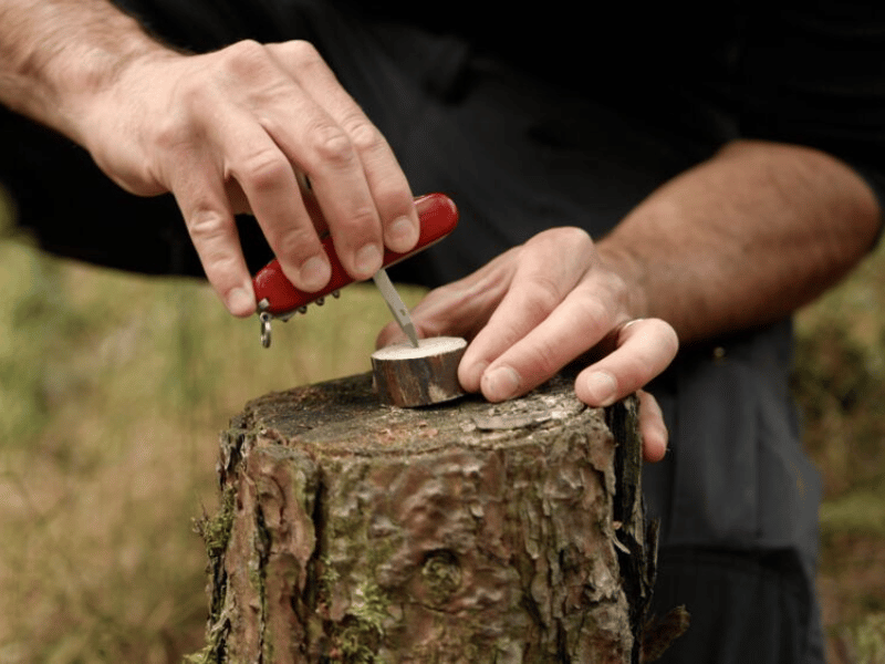 mann bohrt loch mit taschenmesser